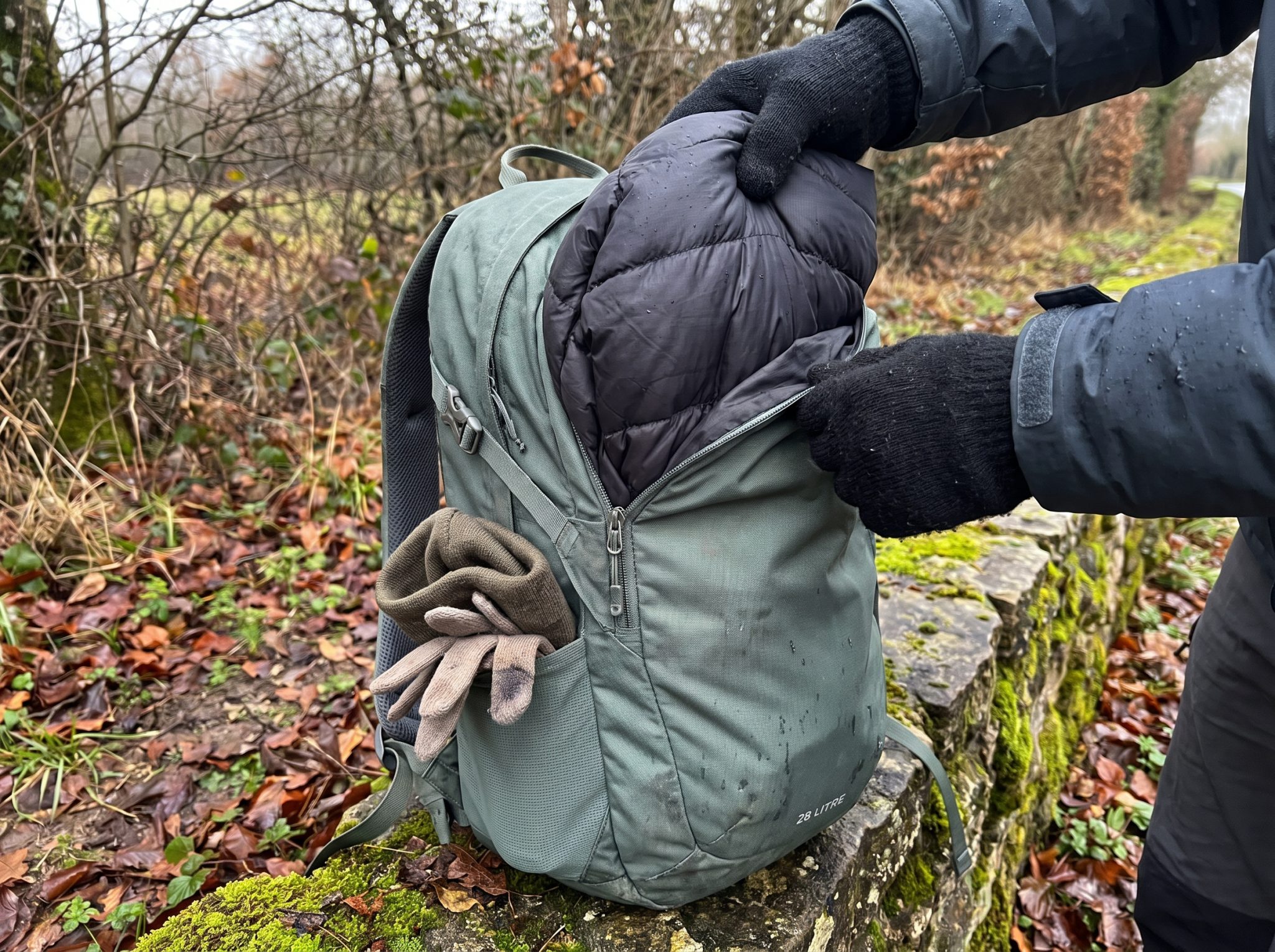 Mains sortant une doudoune compressible du haut d'un sac à dos de randonnée
